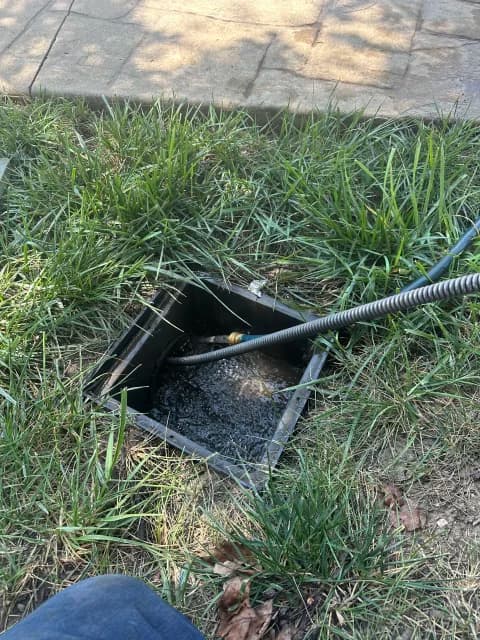 Outdoor yard cleanout with drain cable clearing a main sewer line