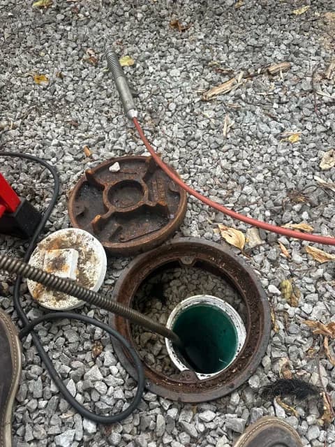 Sewer cleanout in a gravel area with drain cable and open access lid