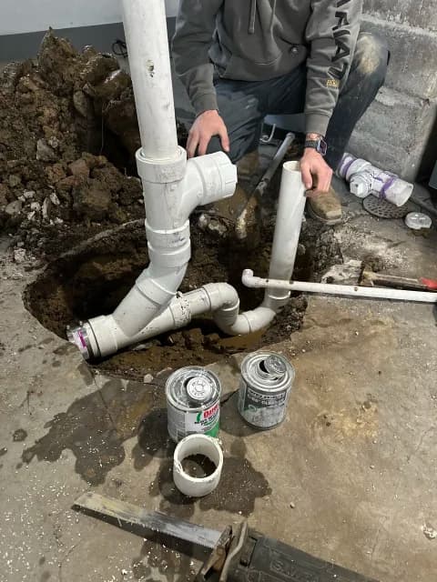 Excavated concrete floor with new PVC drain piping being installed