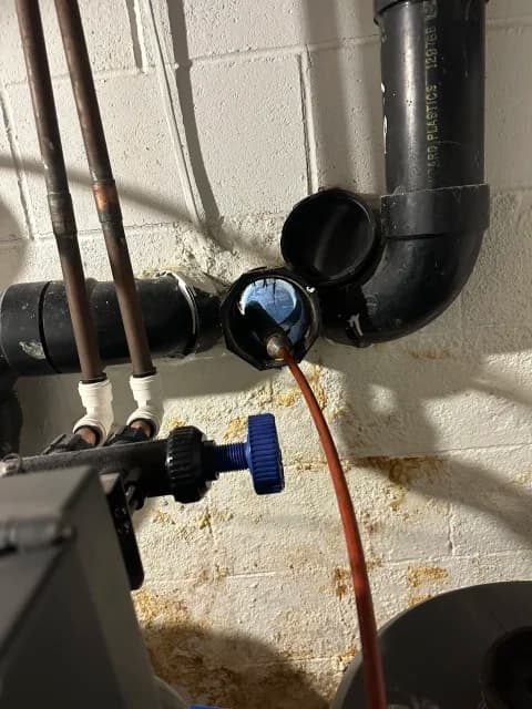 Sewer camera cable entering an interior cleanout on basement plumbing piping